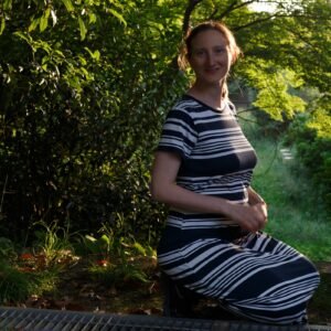 Pregnant woman sitting peacefully in nature, practicing prenatal mindfulness and connecting with her body before birth.