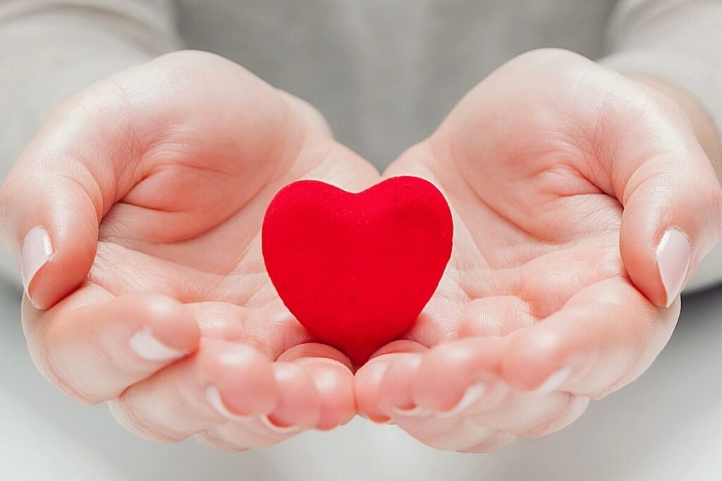 Heart holding hands symbolizing guided relaxations offered with care at Vitality Flame, inviting sharing and support to bring comfort and inner peace to others.